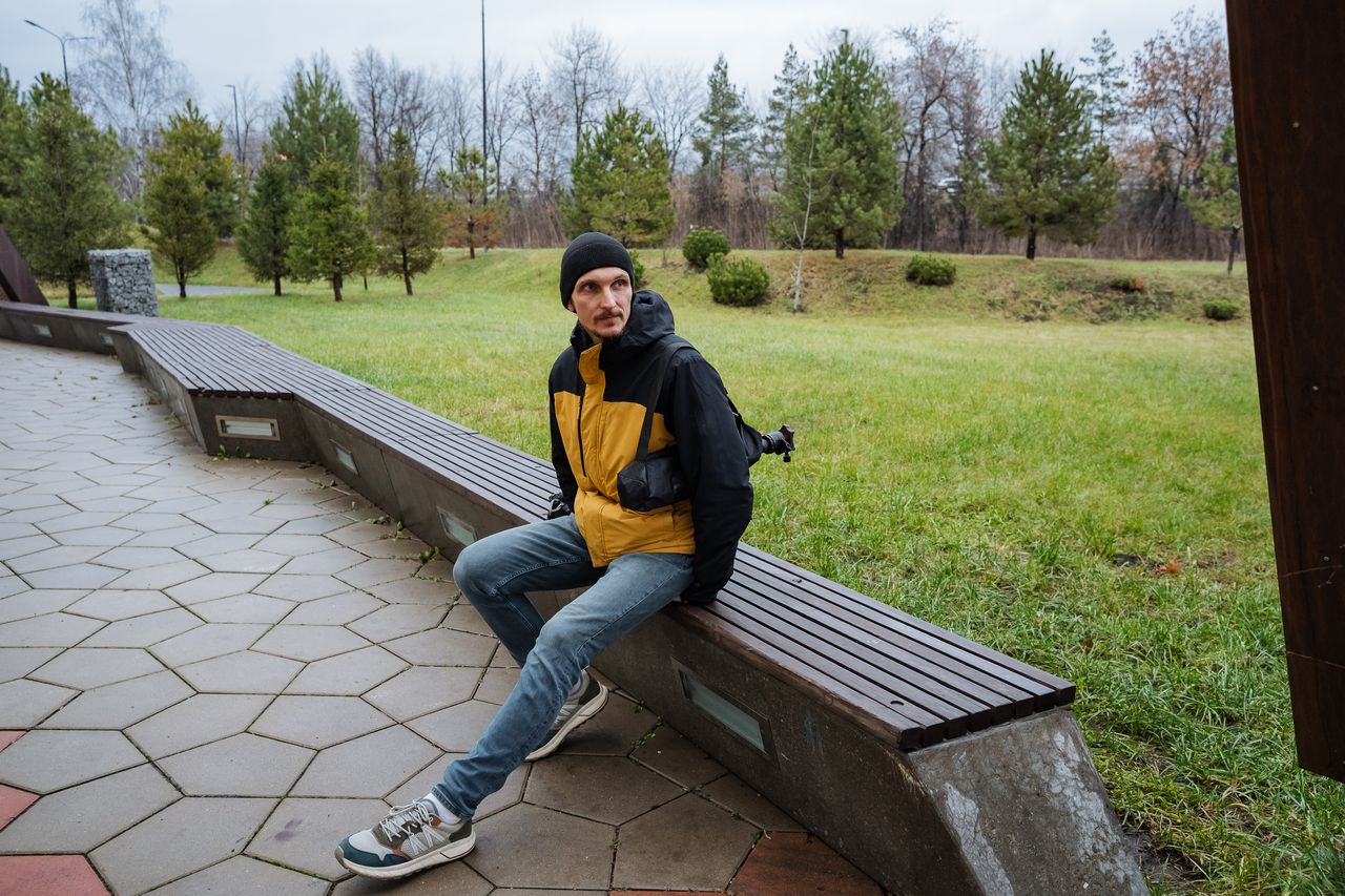 Homme d'une trentaine d'années en veste casual, baskets aux pieds, assis sur un banc de skatepark urbain