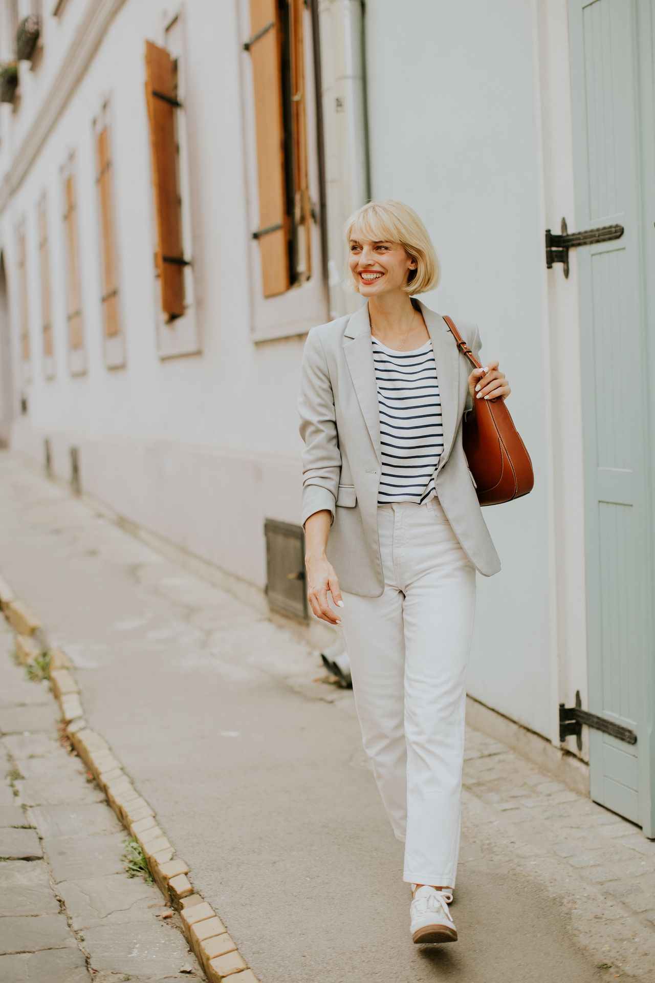 Look streetwear chic : baskets bordeaux, jean wide leg et blazer beige sous la lumière naturelle.
