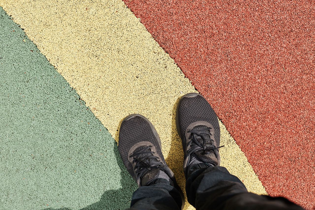 Sneakers éco-responsables sur sol brut, style urbain sobre avec touches bordeaux et palette neutre.